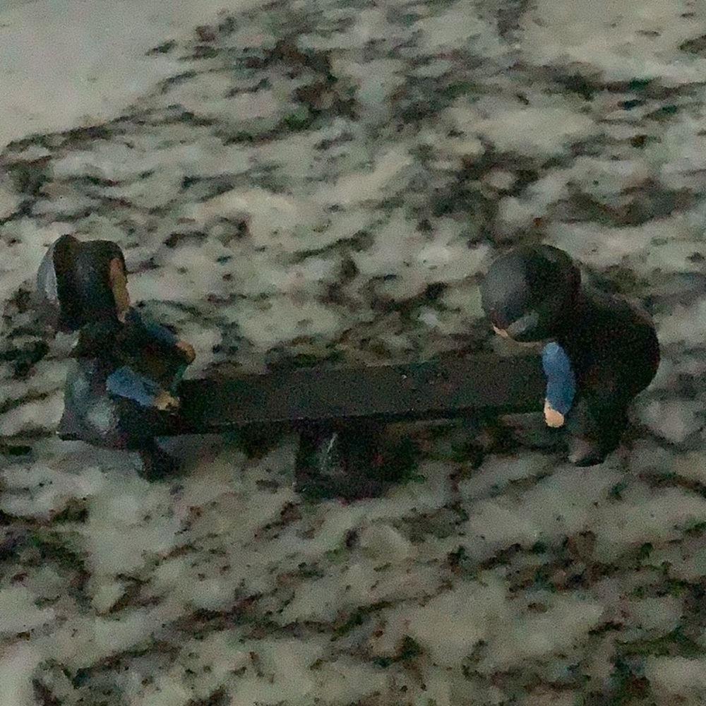 Vintage cast  iron miniature Amish boy and girl figurines on a see saw.